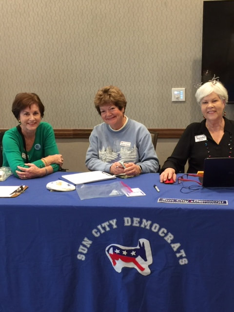 3 women seated at event check-in table